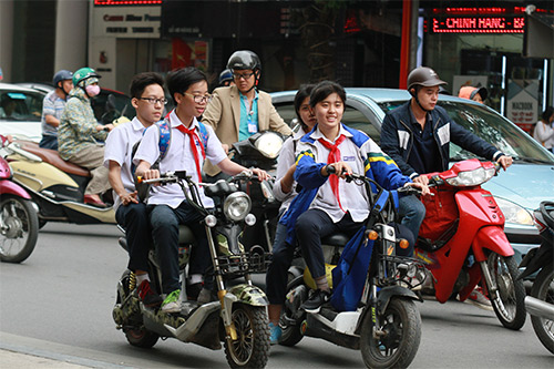 Học sinh đi xe đạp điện trên đường, không đội mũ bảo hiểm